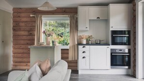 A cozy kitchen with a built-in oven, a dining area with a sofa, and a window with curtains.