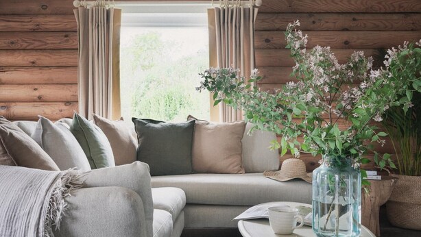 A cozy room with a sofa, a small table with a cup, and a vase with flowers.