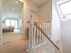Eine Treppe mit weißen Balustern und einer Holzhandläufe, die zu einem Zimmer mit einem Bett und einem Fenster führt.