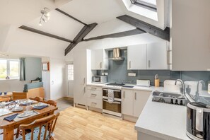 A modern kitchen with a central island, built-in appliances, and a skylight. - 2 Bed in Bideford (oc-73954) (Hartland)
