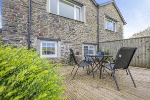 A stone building with a wooden deck, outdoor seating, and a view of the surrounding landscape. - 2 Bed in Bideford (oc-73954) (Hartland)