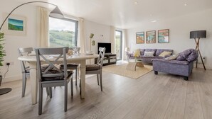 Uma sala de estar moderna com área de jantar, sofá e televisão.