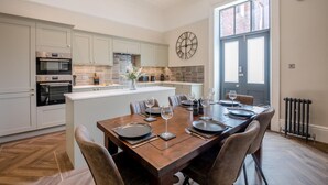 Een moderne keuken met inbouwapparatuur, een eethoek met een grote tafel voor zes personen en een groot raam met uitzicht op de stad.