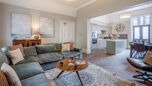 Een ruime woonkamer met een modulaire bank, een salontafel en een vloerkleed.
