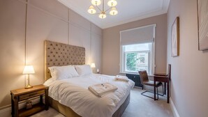 Une chambre d’hôtel avec un grand lit, des lampes de chevet, un bureau et une fenêtre donnant sur un beau paysage.
