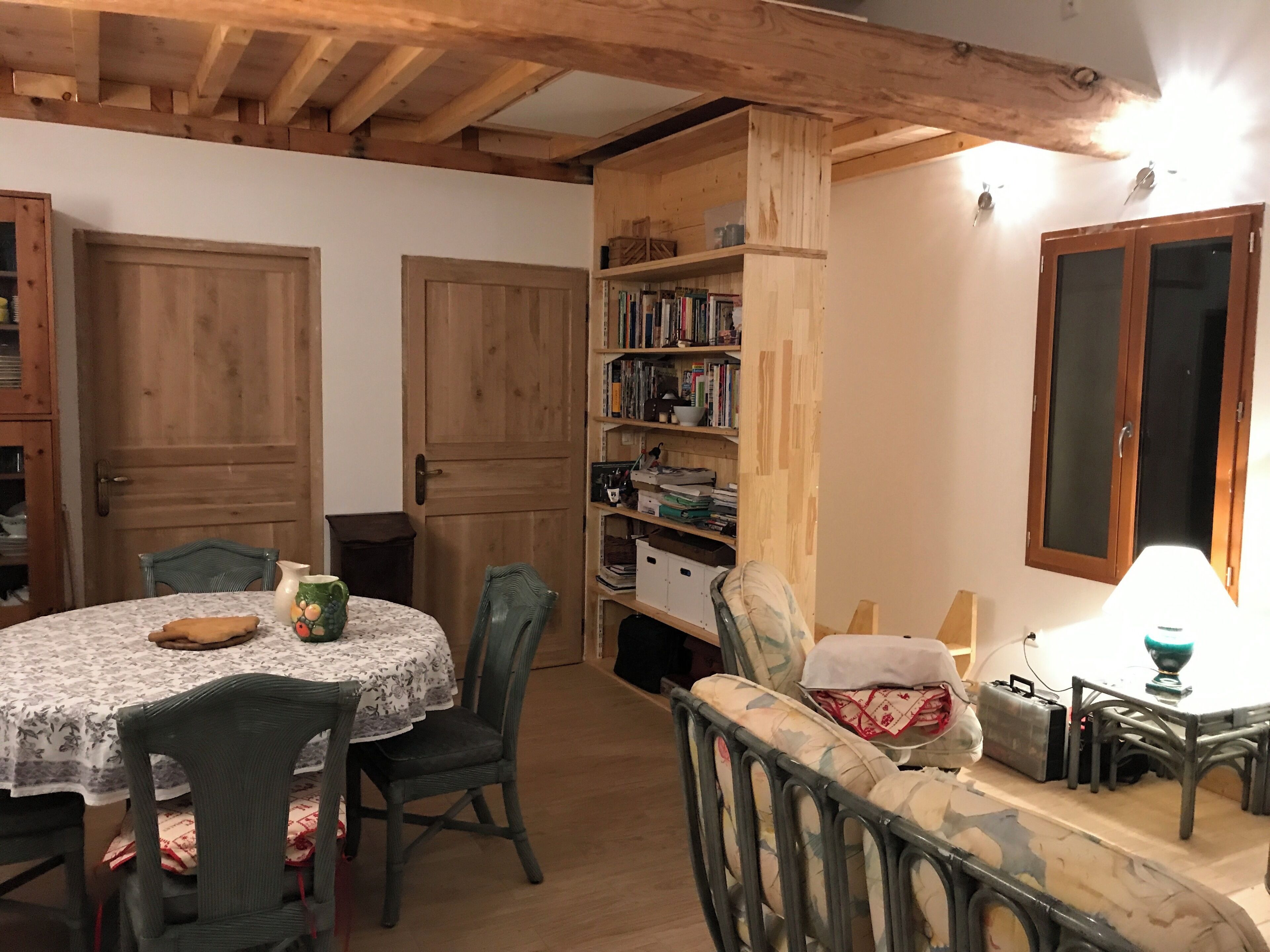 Ein gemütliches Zimmer mit einem runden Tisch, Stühlen, einem Bücherregal und einem Schrank.