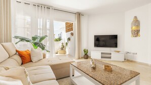 Uma sala de estar moderna com um sofá, mesa de centro, televisão e objetos decorativos.