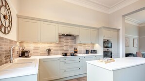 Een moderne keuken met witte kasten, een groot eiland en een inbouwoven.