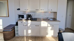 A kitchen with white cabinets, a microwave, a coffee maker, and a sink. - Ferienwohnung mit Balkon in Sonniger Sud-west-lage in Sellin (Sellin)