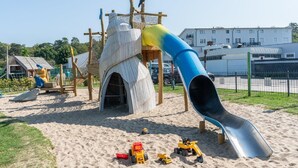 A playground with a slide, climbing structures, and sand. - Ferienwohnung mit Balkon in Sonniger Sud-west-lage in Sellin (Sellin)