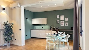 A modern kitchen with white cabinets, a dining table with chairs, and a potted plant. - Da Vittoria Lovely apt near the Arena (Verona)