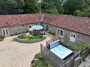 A courtyard with a hot tub, outdoor seating, and a stone building with a tiled roof. - 4 Bed in Sherborne (oc-82941) (Ryme Intrinseca)
