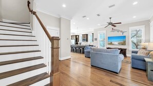 A spacious living area with a staircase, a kitchen, and a dining area. - Close to Trails and Lakes with Shared Pool (Santa Rosa Beach)