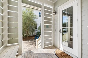 A wooden deck with a glass door leading to a covered outdoor area. - Close to Trails and Lakes with Shared Pool (Santa Rosa Beach)