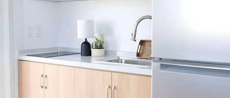 Eine moderne Küche mit einem Edelstahl-Kühlschrank, einer Mikrowelle, einem Spülbecken und Holzschränken.