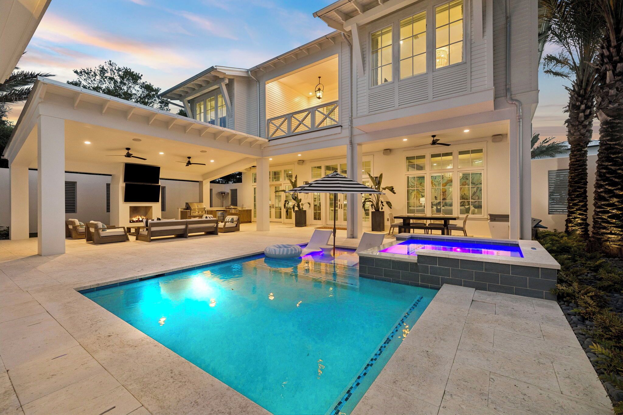 A two-story house with a swimming pool, outdoor seating, and a covered patio area.