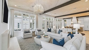 A spacious living area with white sofas, a chandelier, and large windows. - Private Pool, Peloton, Sauna and LSV (Alys Beach)