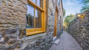 A stone building with a narrow gravel path, wooden-framed windows, and a lantern on the right. - 1 Bed in Banff (oc-t42474) (Banff)