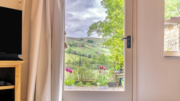 Quarto com porta que dá para um jardim de tulipas e vista de colinas ondulantes.