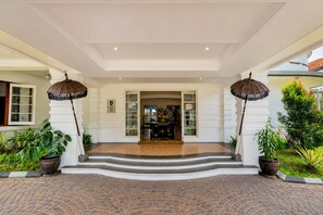 A hotel entrance with a covered porch, steps leading to the door, and potted plants. - Townhouse Oak Casa D'Ladera Bandung (Bandung)