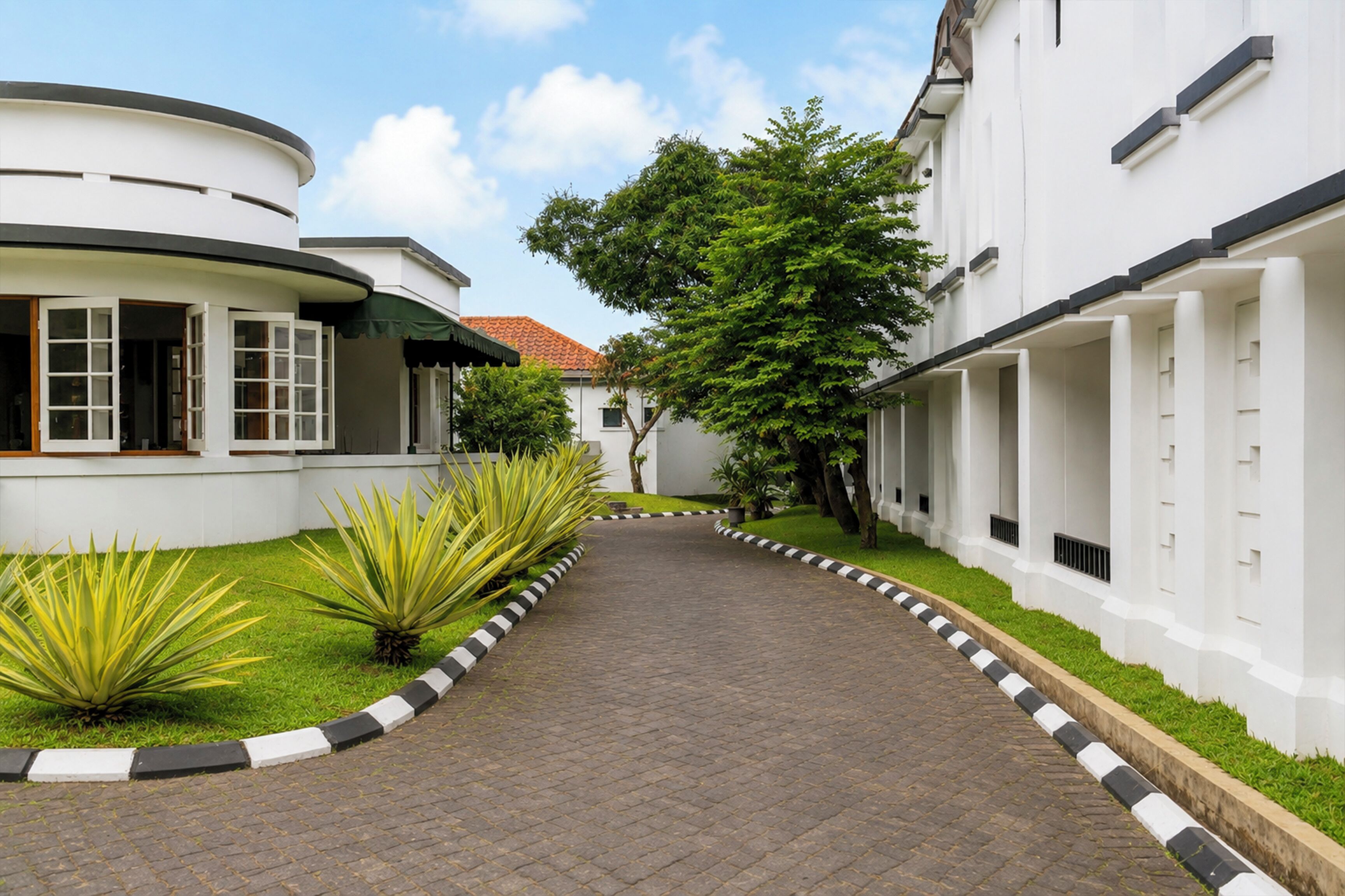 A pathway leading to a building with a curved facade and a green awning.