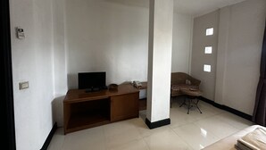 A room with a flat-screen TV on a wooden stand, a telephone, a wicker chair, and a small table. - Townhouse Oak Casa D'Ladera Bandung (Bandung)