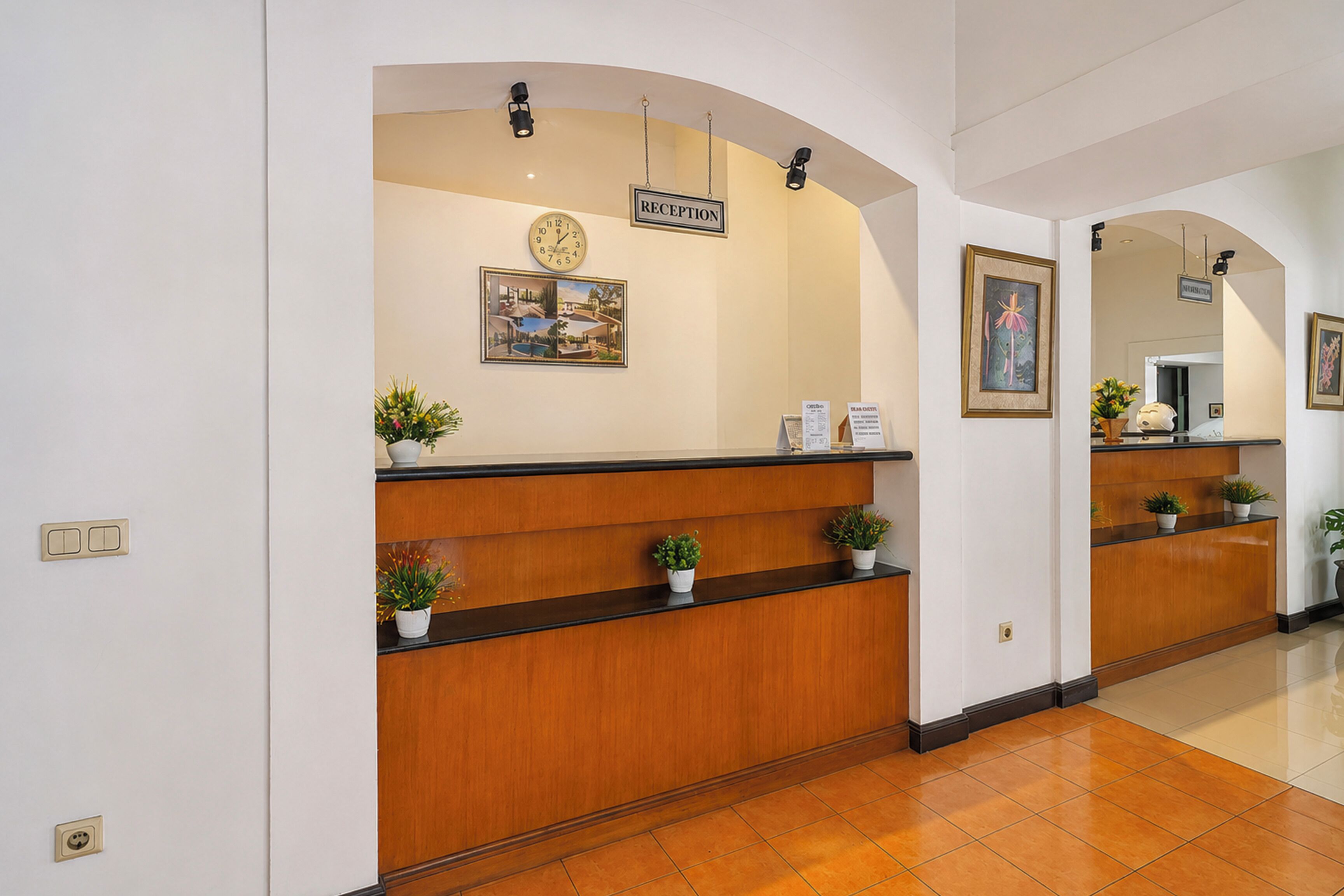 A reception area with a wooden reception desk, a clock, and framed artwork on the wall.