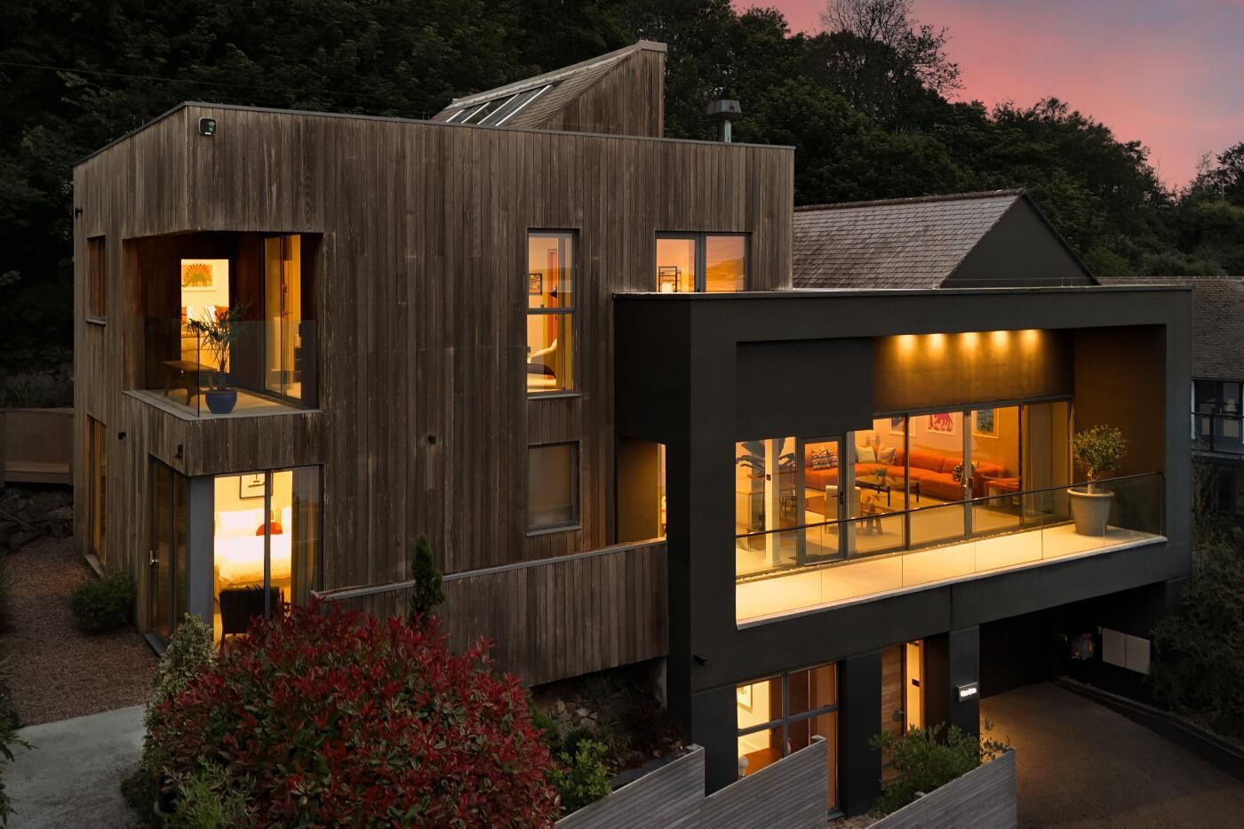 A modern two-story house with large windows and a balcony.