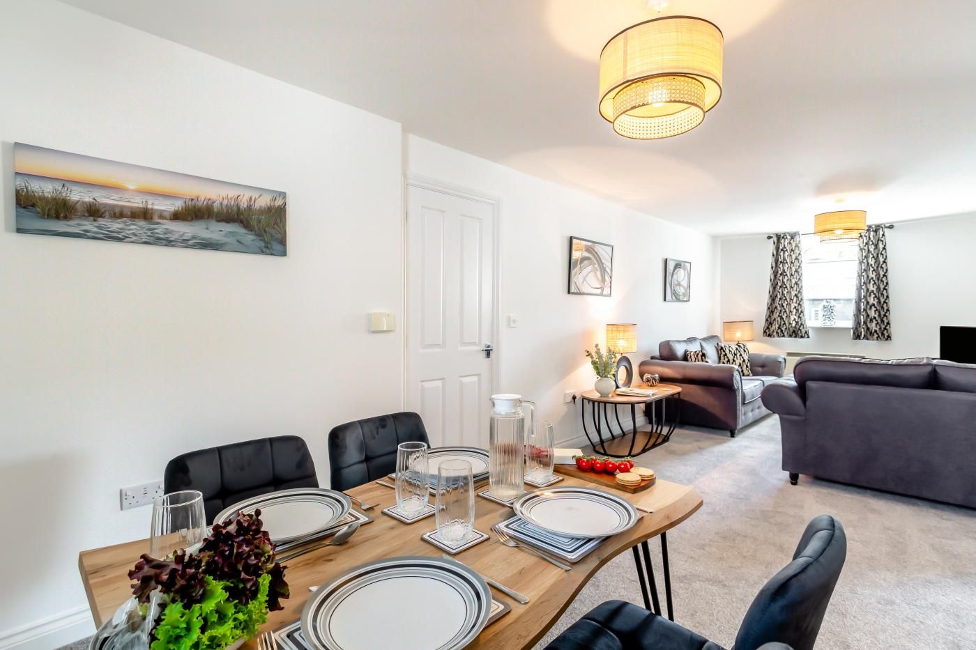 A modern living room with a dining area, a sofa, and a painting on the wall.