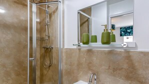 A bathroom with a glass-enclosed shower, a white sink, and a mirror above the sink.