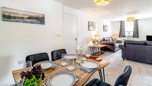 Een moderne woonkamer met een eethoek, een bank en een schilderij aan de muur.