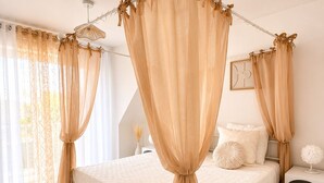 A bedroom with a canopy bed, a bedside table, a nightstand, and a rug.