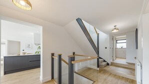 A modern interior with a kitchen, staircase, and a view of the outside. - 5 Bed in Ogmore-by-Sea (oc-o42632) (Ogmore-by-Sea)