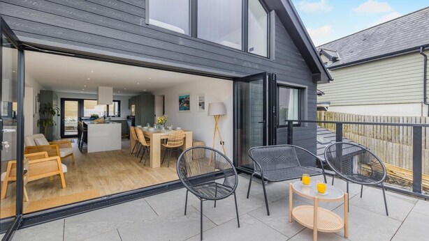 A modern house with a patio, dining area, and kitchen. - 5 Bed in Ogmore-by-Sea (oc-o42632) (Ogmore-by-Sea)