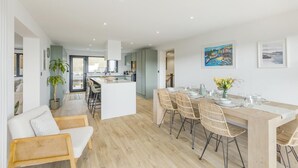 A modern interior with a dining area, kitchen, and living space. - 5 Bed in Ogmore-by-Sea (oc-o42632) (Ogmore-by-Sea)