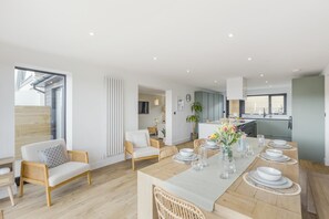 Una sala de estar moderna con comedor, muebles de madera y vistas al exterior.