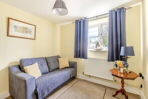 A room with a grey sofa, a small table with a lamp, and a window with curtains. - 2 Bed in Westport (oc-c42687) (Westport)