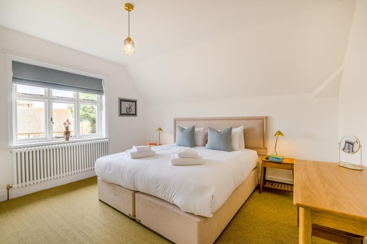 A hotel room with a large bed, a bedside table, a window with a view, and a radiator.