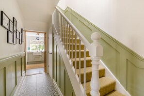 A staircase with white balusters and a green handrail leading to a room with a window and a door. - 2 Bed in Holkham (oc-k42475) (Holkham)