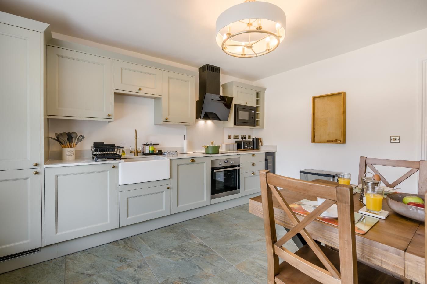 Una cocina moderna con armarios blancos, una isla central y un comedor con sillas de madera.
