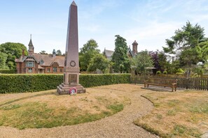 A monument in a landscaped area with a pathway leading to a bench. - 2 Bed in Holkham (oc-k42475) (Holkham)