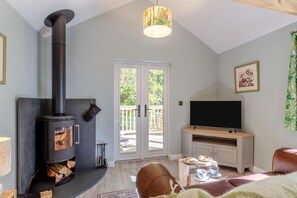 Ein Wohnzimmer mit Kaminofen, Fernseher und Essbereich mit Tisch und Stühlen.