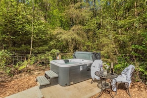 A hot tub in a forested area with a table and chairs nearby. - 1 Bed in Buckland Filleigh (oc-h41749) (Buckland Filleigh)