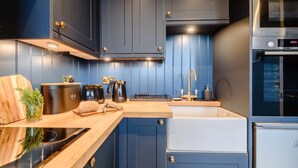 A modern kitchen with dark blue cabinets, a stainless steel oven, and a wooden countertop. - 1 Bed in Presteigne (oc-t38200) (Presteigne)