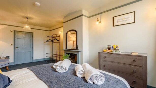 A hotel room with a bed, a dresser, a mirror, a hanging light fixture, and a framed picture on the wall. - 1 Bed in Presteigne (oc-t38200) (Presteigne)