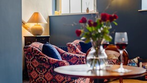 A cozy living room with patterned sofas, a table with a vase of flowers, and a wine glass. - 1 Bed in Presteigne (oc-t38200) (Presteigne)