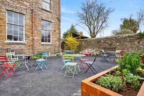 A stone building with outdoor seating and a garden area.