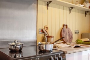 A kitchen with a stove, pots, a wooden cutting board, and a book on the counter.