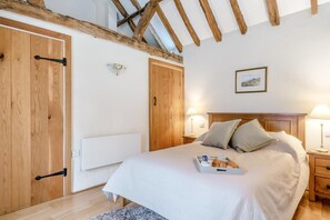 Ein Schlafzimmer mit Holzboden, einem Bett mit Kissen, Nachttischlampen und einem Tablett mit Gegenständen auf dem Bett.