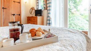 Un letto con un vassoio di prodotti per la colazione, tra cui croissant, marmellata e tè.